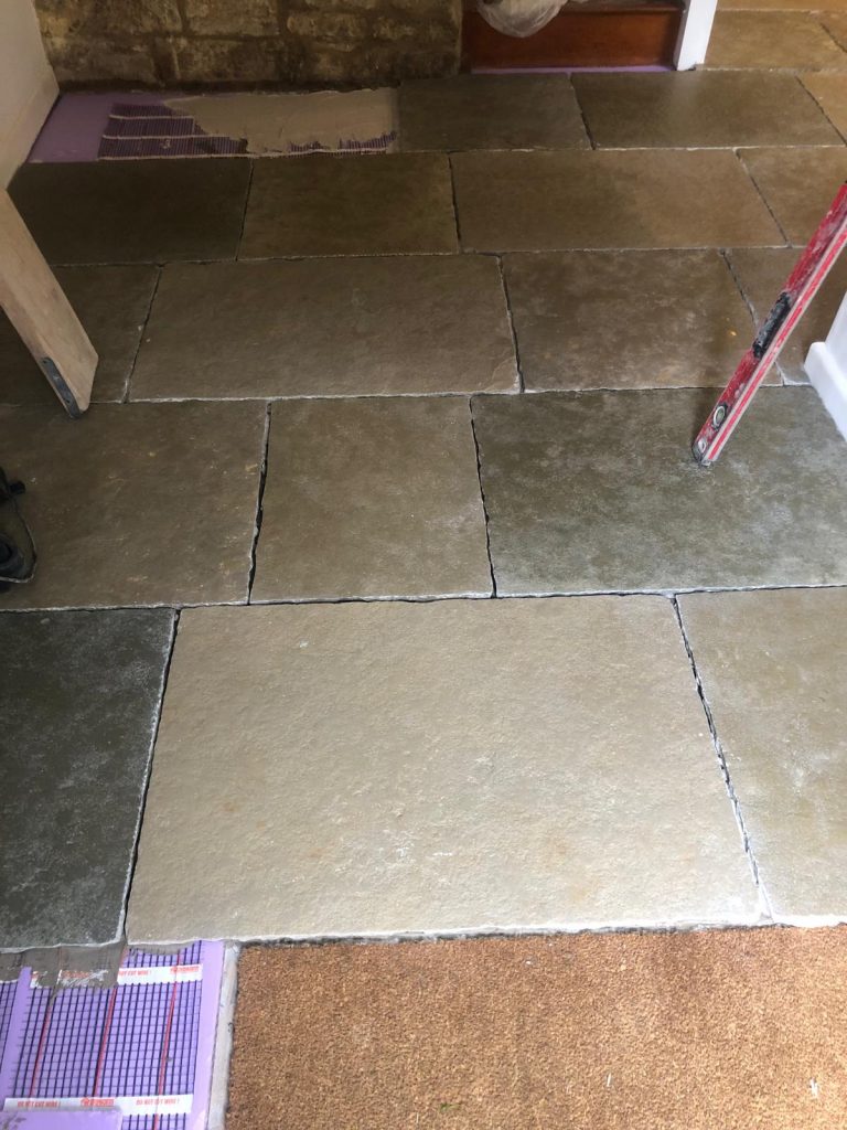 Cathedral Limestone partially installed showing under floor heating cables and an ungrouted floor, with the mat well cut to size.