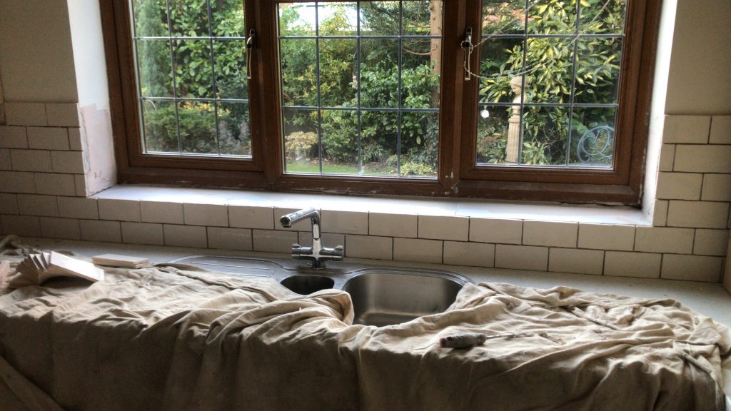 ceramic tiling sink splash and window ledge with no grout and dust sheets covering the sink