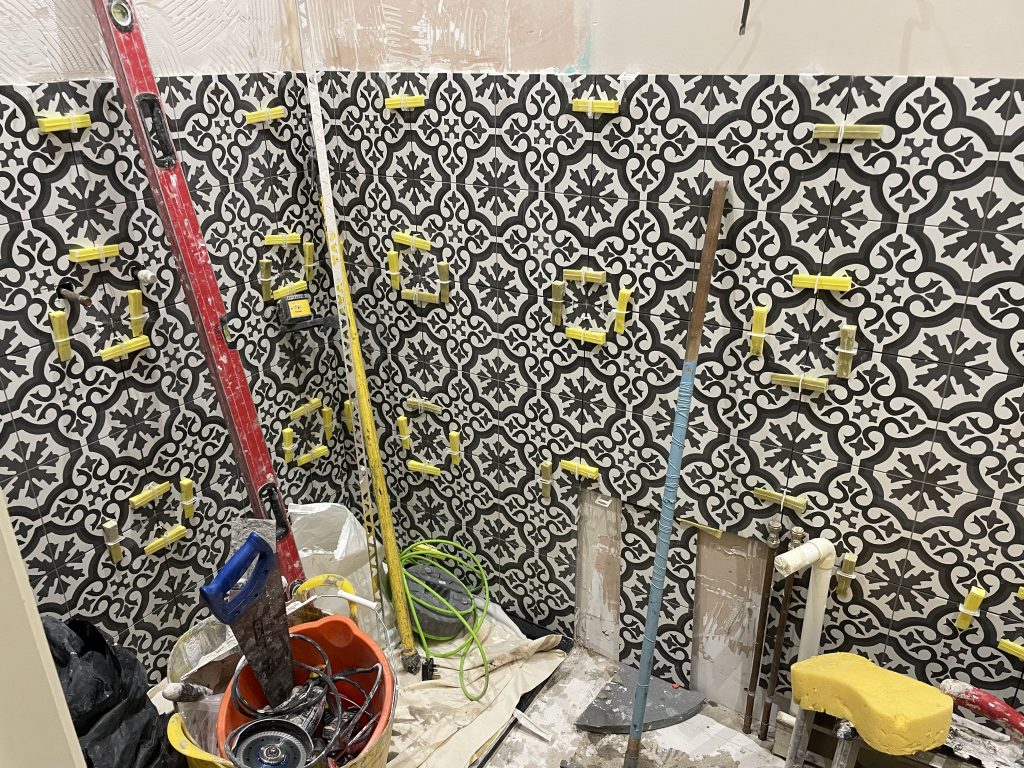 Decorative porcelain shower wall tiles installation in Dorset showing spacers, levelling clips and tiling tools during installation

