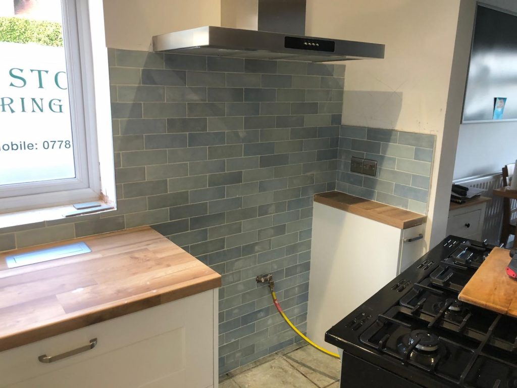 Decorative aqua coloured porcelain wall tiles installed in a kitchen splashback with cooker area exposed during installation