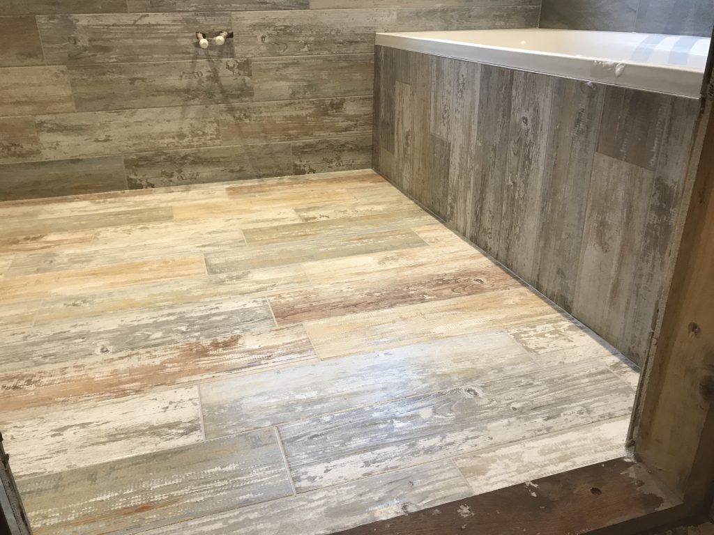 porcelain wood effect floor tiles flowing up the bath panel and surrounding walls