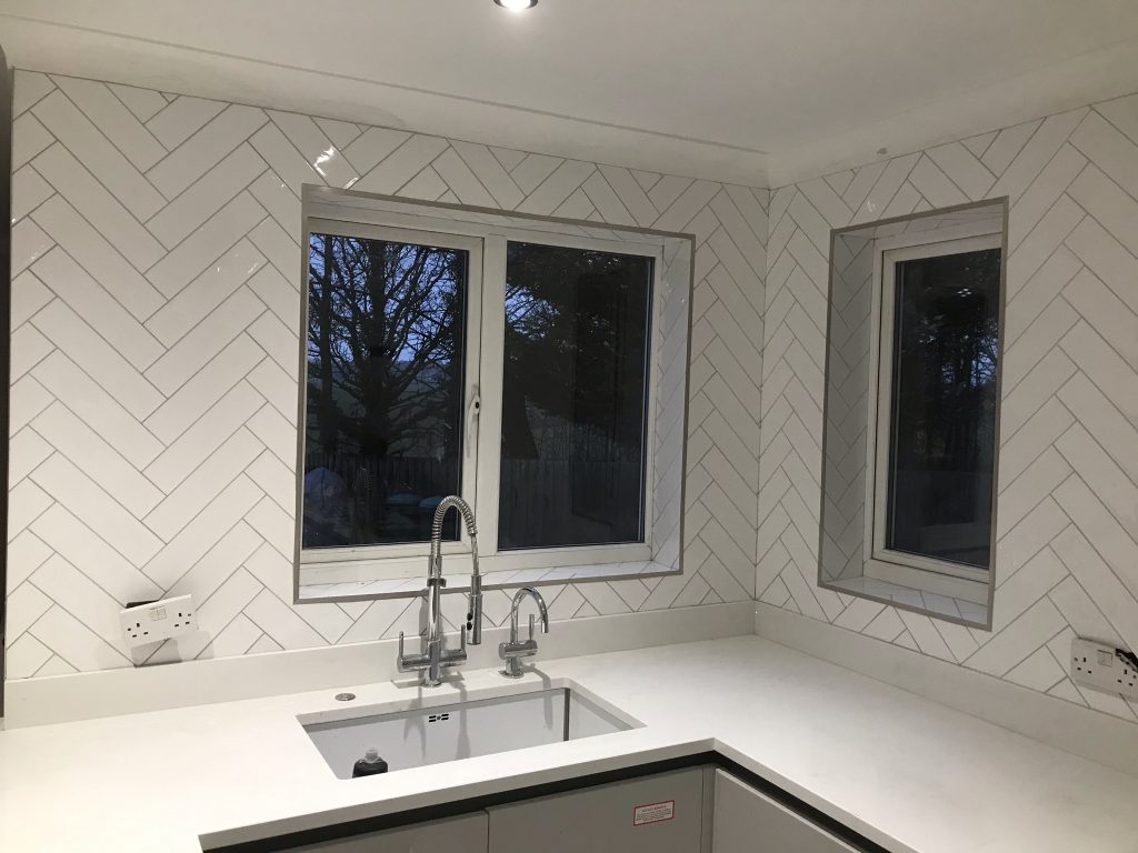 White decorative, herringbone pattern wall tiling showing ledge details.