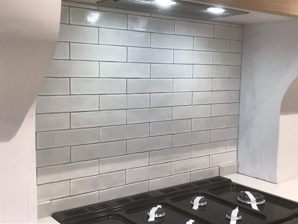 Decorative cooker hob splash tiled in bumpy white 300x75mm tiles